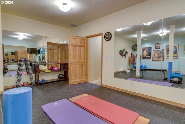 exercise area featuring visible vents, a textured ceiling, and baseboards