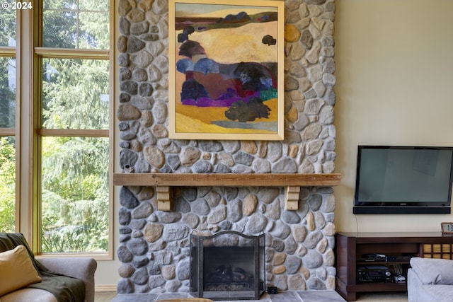 living area featuring plenty of natural light and a stone fireplace