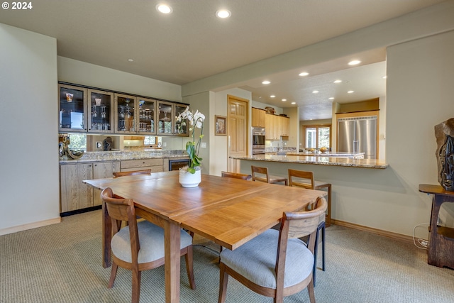 dining area featuring baseboards, bar, recessed lighting, and light colored carpet