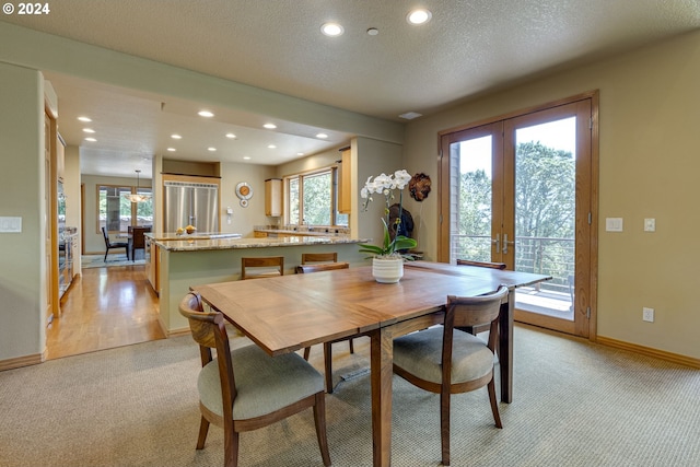 dining area with recessed lighting, light colored carpet, a textured ceiling, and french doors