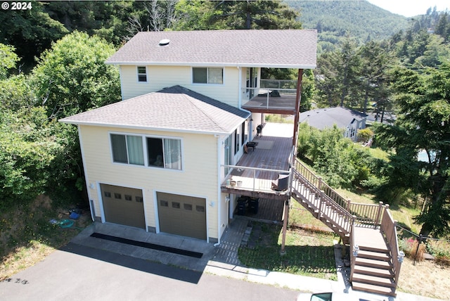 view of front of property with aphalt driveway, a forest view, stairway, an attached garage, and a shingled roof