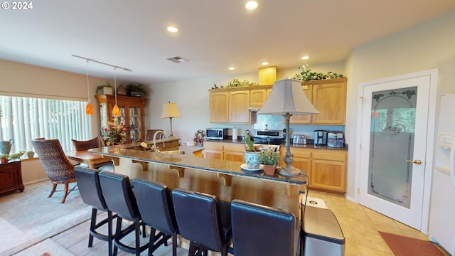 kitchen with light tile patterned floors, visible vents, a breakfast bar, recessed lighting, and a sink