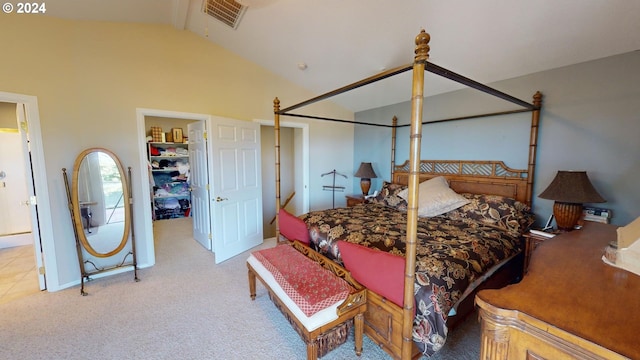 carpeted bedroom with a closet, visible vents, a walk in closet, and vaulted ceiling