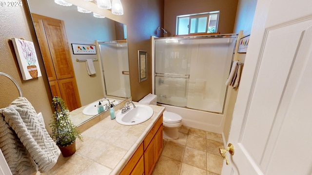 full bath with vanity, tile patterned floors, toilet, and combined bath / shower with glass door