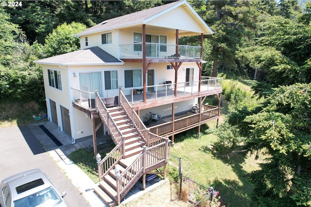 view of front of property featuring a balcony, a shingled roof, stairs, a garage, and aphalt driveway