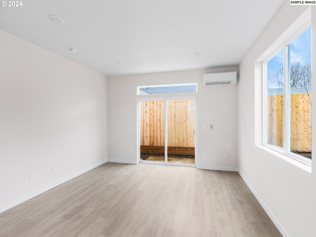 spare room featuring a wall mounted air conditioner and light hardwood / wood-style floors