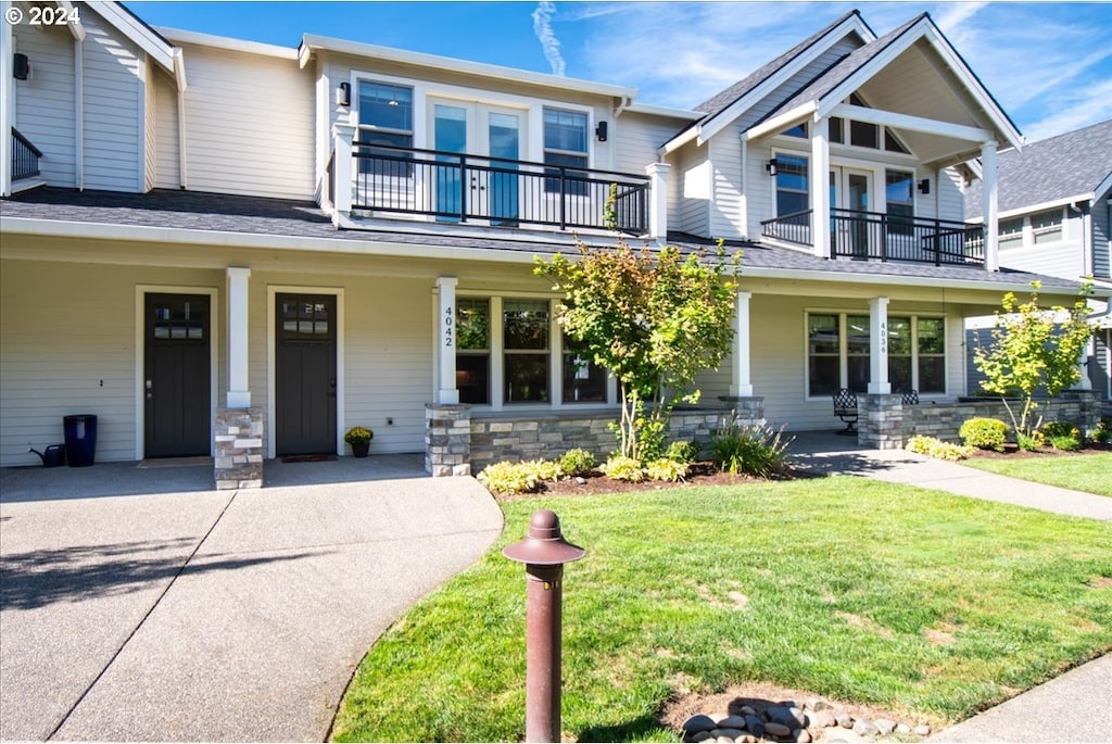 view of front of house with a balcony, a porch, and a front lawn