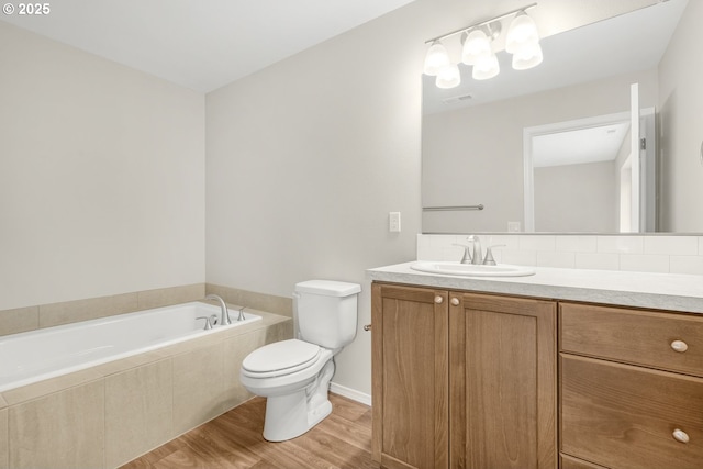 bathroom featuring visible vents, toilet, vanity, wood finished floors, and a bath