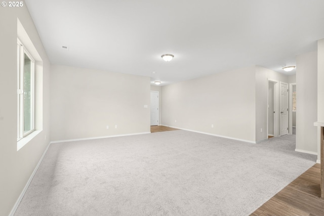 unfurnished room with carpet flooring, baseboards, and wood finished floors