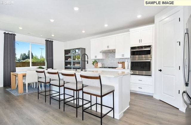 kitchen featuring white cabinetry, a kitchen island with sink, light hardwood / wood-style flooring, and sink