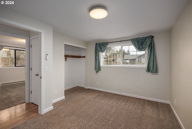 unfurnished bedroom featuring carpet flooring, a closet, a baseboard heating unit, and multiple windows