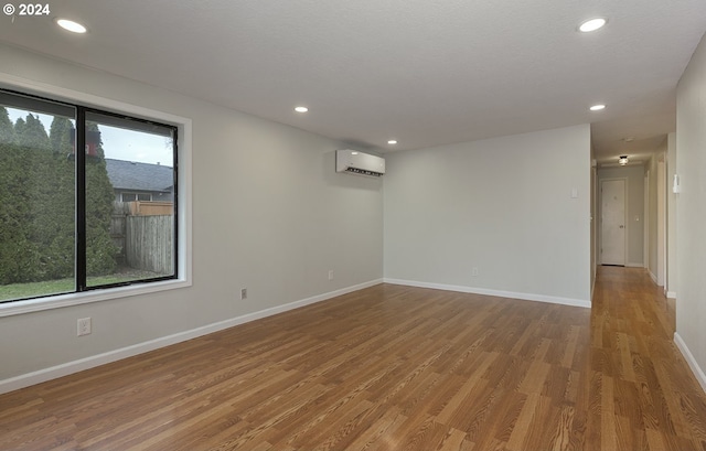 empty room featuring a wall mounted air conditioner and hardwood / wood-style floors