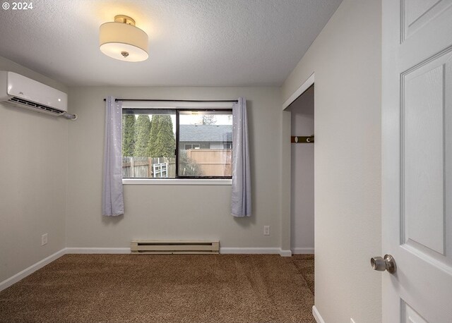 carpeted spare room with a textured ceiling, a baseboard radiator, and a wall mounted AC