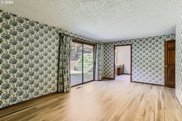 empty room featuring a textured ceiling and hardwood / wood-style floors