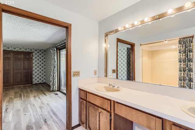 bathroom with wood-type flooring, a shower with shower curtain, vanity, and a textured ceiling