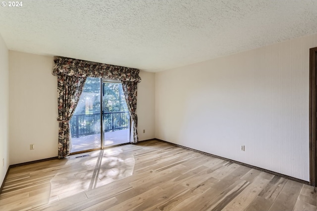 unfurnished room with light hardwood / wood-style floors and a textured ceiling