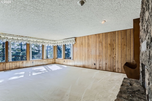 empty room with wood walls, carpet, and a textured ceiling