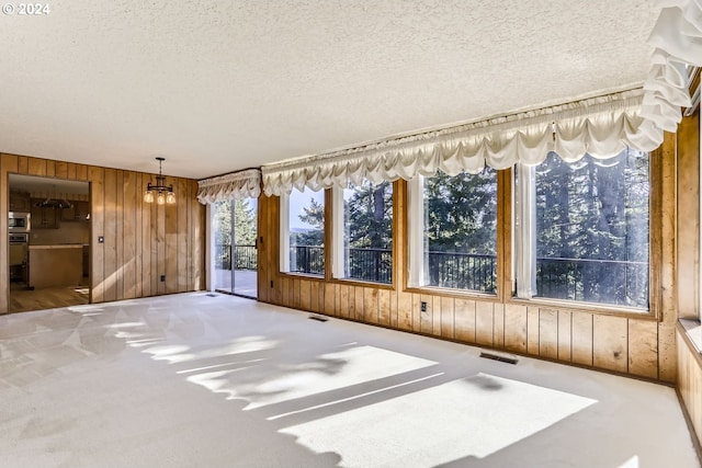 interior space with carpet floors, a textured ceiling, and wooden walls