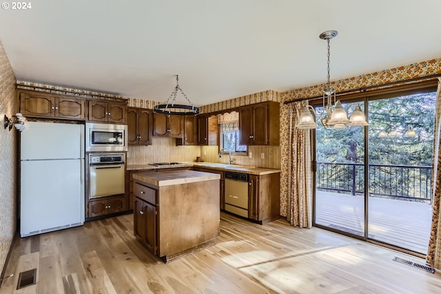 kitchen with stainless steel appliances, a center island, light wood-type flooring, and dark brown cabinets