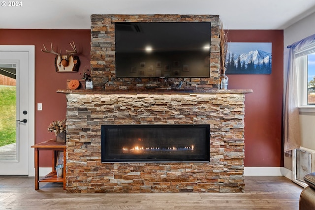 interior details featuring a stone fireplace, baseboards, and wood finished floors