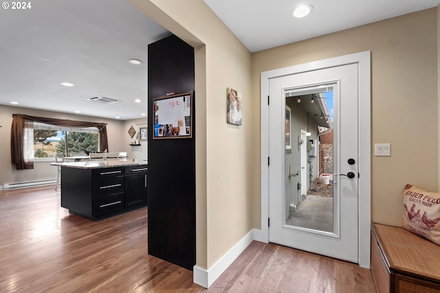 doorway featuring baseboard heating and wood-type flooring