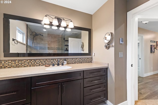 bathroom with vanity, baseboards, backsplash, and tiled shower