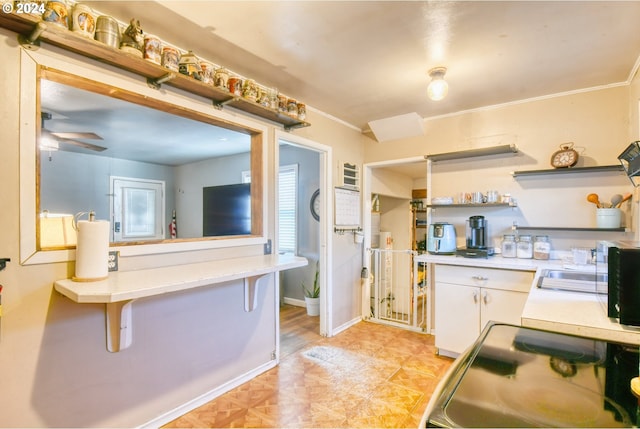 kitchen featuring ornamental molding, white cabinetry, ceiling fan, and a breakfast bar