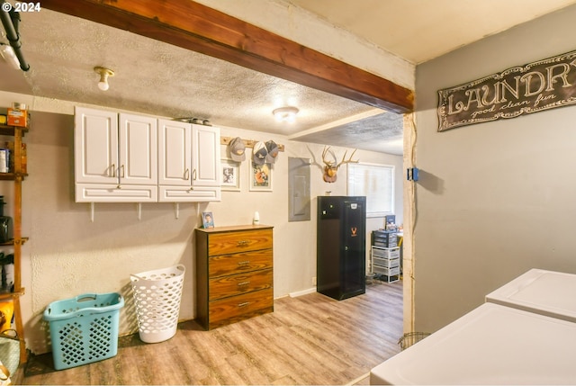 laundry room featuring cabinets, a textured ceiling, light hardwood / wood-style flooring, electric panel, and washing machine and dryer