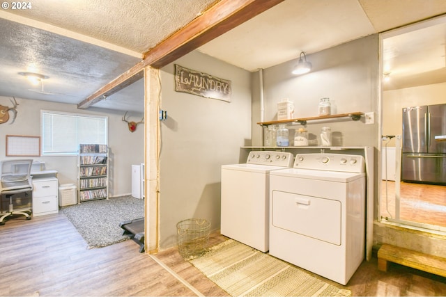 washroom with light wood-type flooring, a textured ceiling, and independent washer and dryer