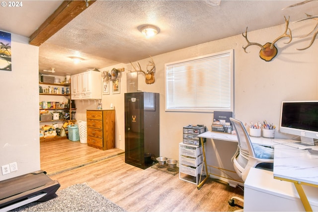 home office with beam ceiling, a textured ceiling, and light hardwood / wood-style flooring