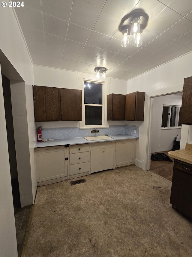 kitchen featuring dark brown cabinetry, sink, and concrete flooring