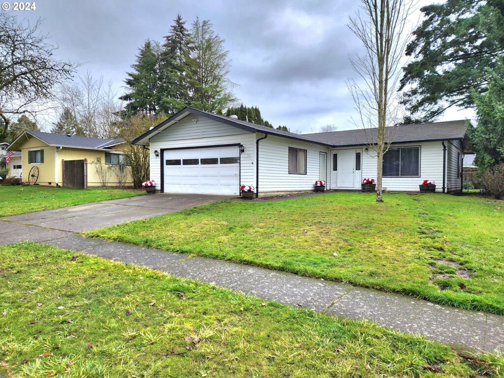 ranch-style home featuring a garage and a front lawn