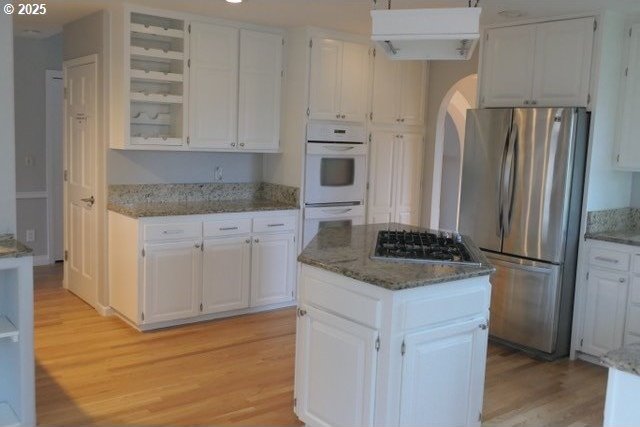 10420 SW 153rd Ave, Beaverton, OR 97007 - kitchen featuring stainless steel appliances, light wood-type flooring, arched walkways, and white cabinets