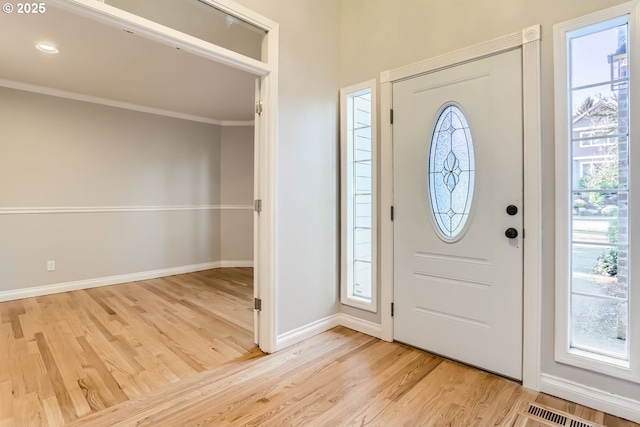 foyer with crown molding, light hardwood / wood-style flooring, and a wealth of natural light