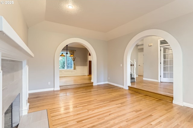 unfurnished living room with a tiled fireplace and light hardwood / wood-style flooring