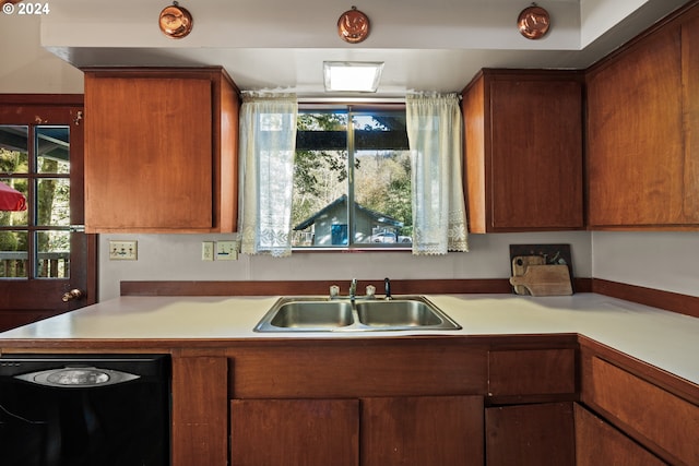 kitchen featuring black dishwasher, light countertops, plenty of natural light, and a sink