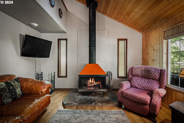 living room featuring wooden ceiling, light wood-type flooring, vaulted ceiling, a wood stove, and wooden walls