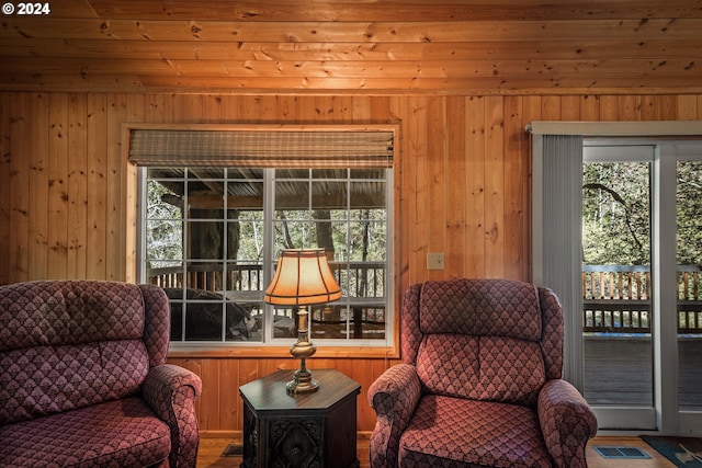 sitting room with wooden walls, a healthy amount of sunlight, and wood ceiling