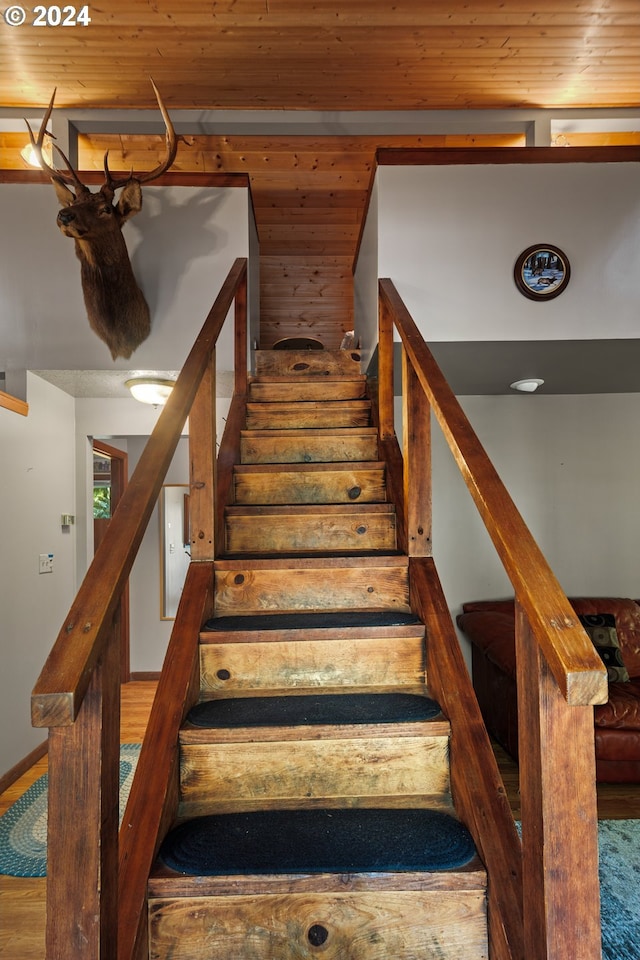 stairs featuring wood ceiling and wood finished floors