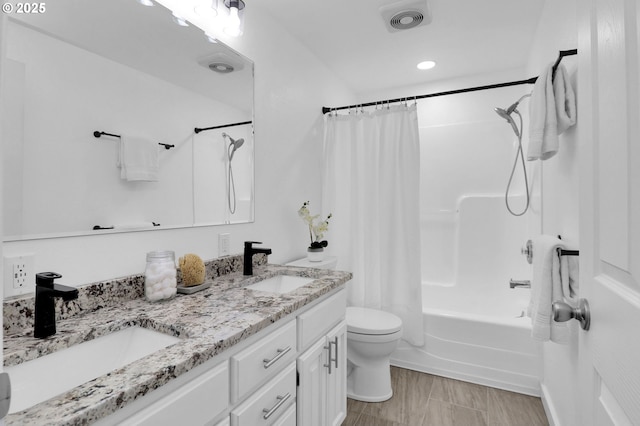 bathroom with double vanity, toilet, visible vents, and a sink