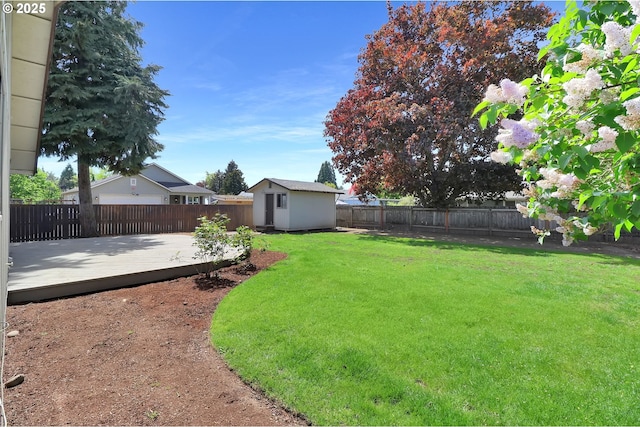 view of yard featuring a fenced backyard, a wooden deck, an outbuilding, and a shed