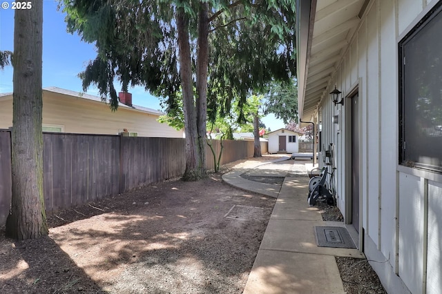 view of yard featuring a storage unit, a fenced backyard, a patio area, and an outdoor structure