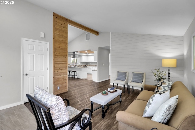 living area featuring wooden walls, lofted ceiling with beams, plenty of natural light, and visible vents