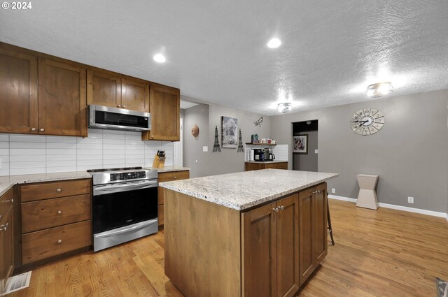 kitchen featuring decorative backsplash, a center island, stainless steel appliances, and light hardwood / wood-style flooring