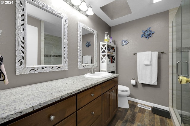 bathroom with wood-type flooring, vanity, toilet, and walk in shower