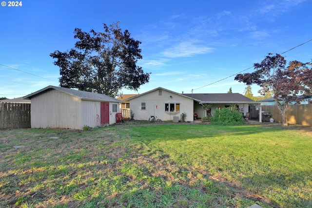 back of property with a lawn and a storage unit