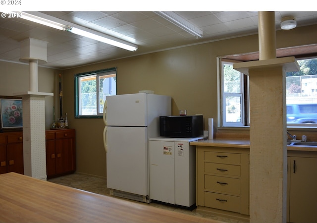 kitchen with freestanding refrigerator, light countertops, and black microwave