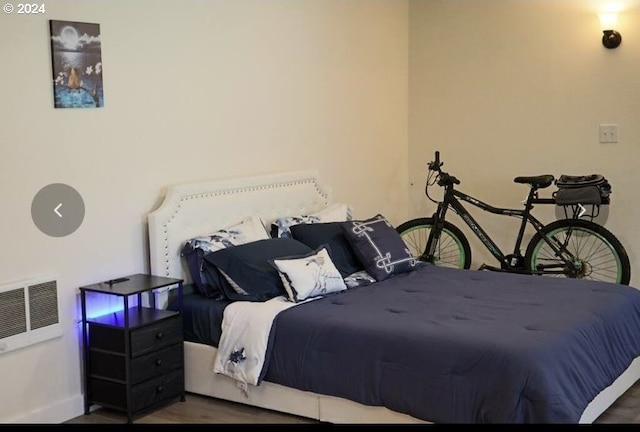 bedroom featuring visible vents, baseboards, and wood finished floors