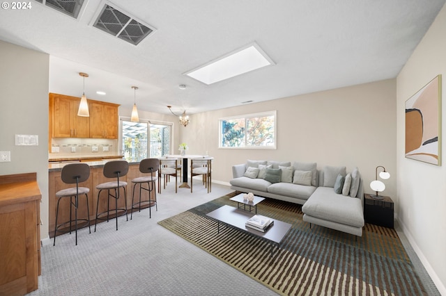 carpeted living room with a skylight and a chandelier