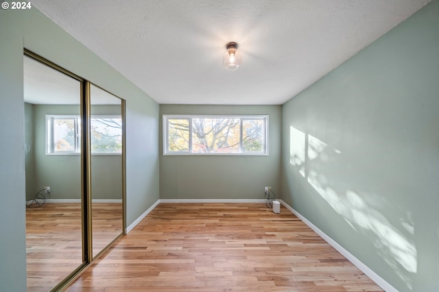 unfurnished bedroom with a closet, a textured ceiling, and light wood-type flooring